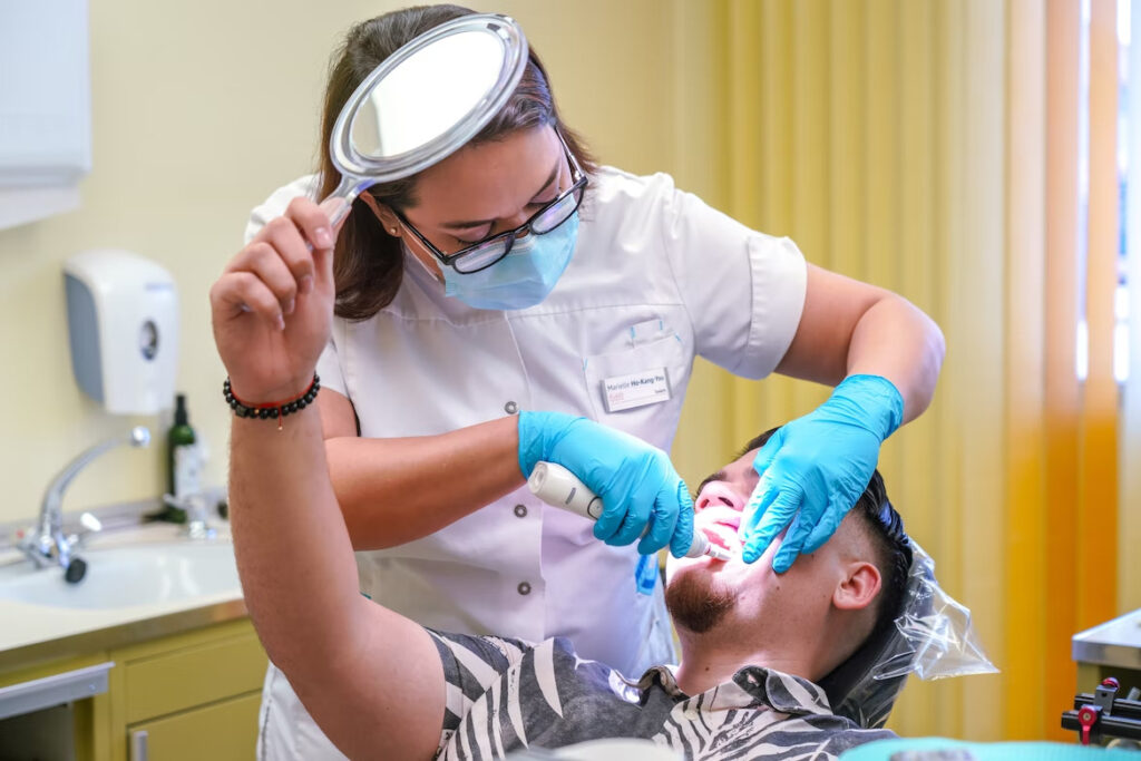 a dentist working on a dental procedure as the patient observes with a mirror