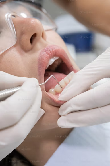 photo of a dentist using a dental probe to examine the woman's teeth