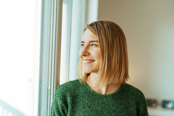 woman in green smiling while looking out the window